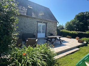 A stone house with a tiled patio, outdoor seating, and a grassy garden. - Goas Raoul - PLEUMEUR GAUTIER (PLEUMEUR GAUTIER)