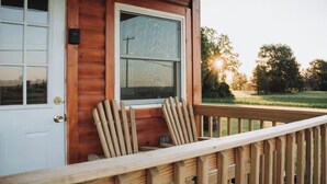 A wooden cabin with a porch, a door, and a window. - Cozy tiny home with Sunrise Views in the Heart of Finger Lakes (Penn Yan)