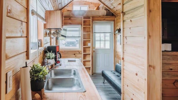A compact kitchen with a sink, stove, and wooden cabinets. - Cozy tiny home with Sunrise Views in the Heart of Finger Lakes (Penn Yan)