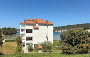 Un bâtiment blanc avec un toit recouvert de tuiles rouges, un balcon et une vue sur la mer.