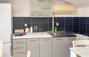 Eine moderne Küche mit grauen Schränken, einer weißen Arbeitsplatte, einem Edelstahl-Spülbecken und einem eingebauten Backofen.