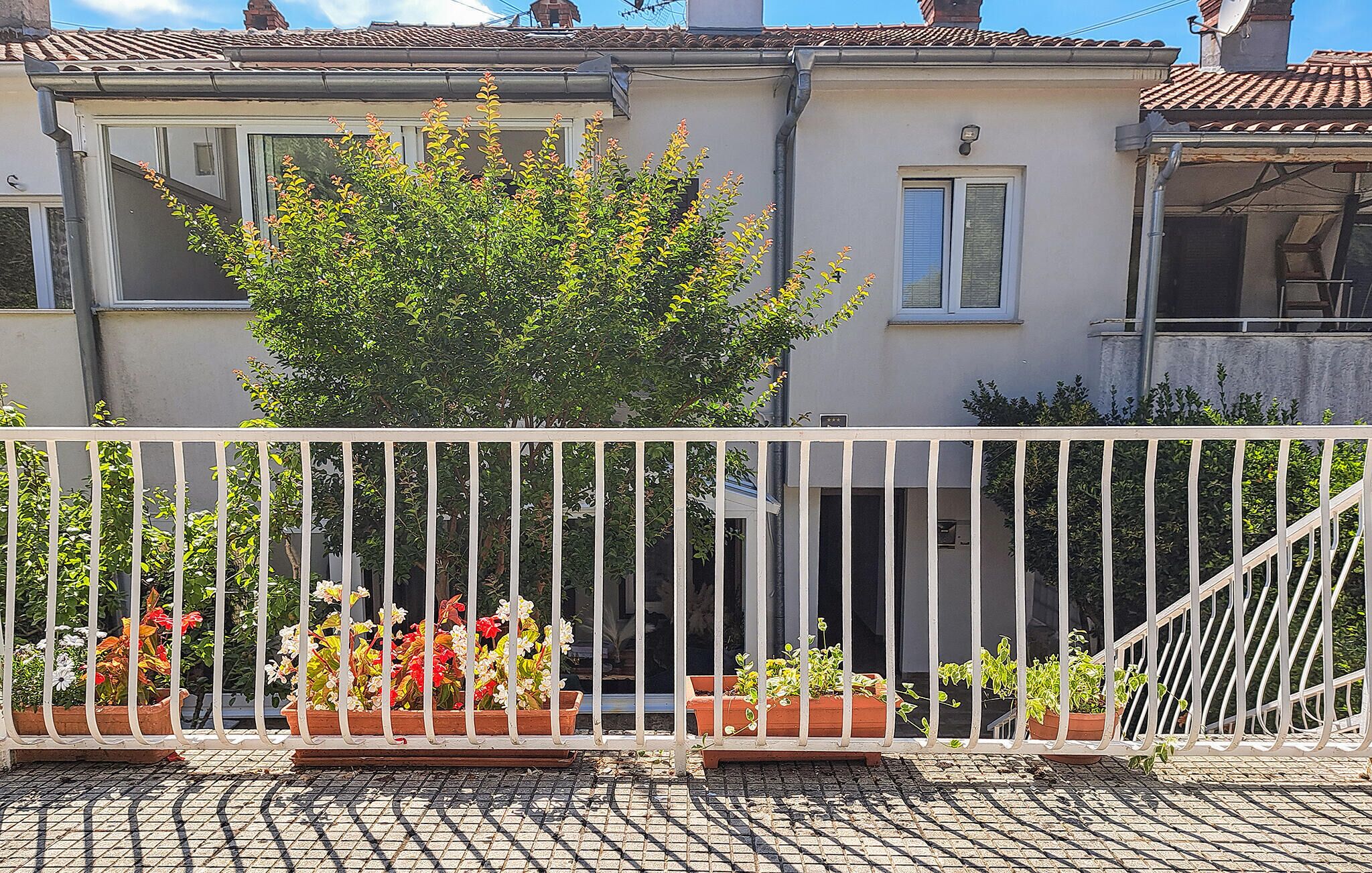 Un balcón con plantas en macetas y baranda de metal.