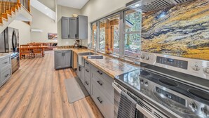 Una cocina moderna con una isla grande, electrodomésticos de acero inoxidable y vistas al exterior.