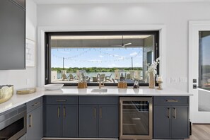 A modern kitchen with dark cabinets, a large window, and a view of a patio area.
