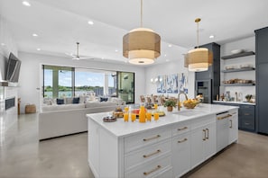 A modern kitchen with a large island, white cabinetry, and pendant lighting.