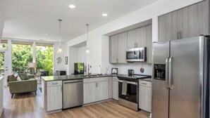 A modern kitchen with stainless steel appliances, light wood cabinetry, and a large island. - Beautiful 2-bedroom townhome downtown Raleigh  Walk to Everything (Raleigh)