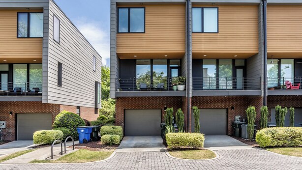A modern two-story residential building with a brick facade, large windows, and a paved driveway. - Beautiful 2-bedroom townhome downtown Raleigh  Walk to Everything (Raleigh)