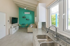 Eine moderne Küche mit einer Granitarbeitsplatte, einer Edelstahlspüle und einem Fenster mit Blick auf Grünflächen.