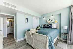 Ein Schlafzimmer mit einem Bett, einem Nachttisch, einer Wand mit maritimer Dekoration und einer Tür zu einem Badezimmer.