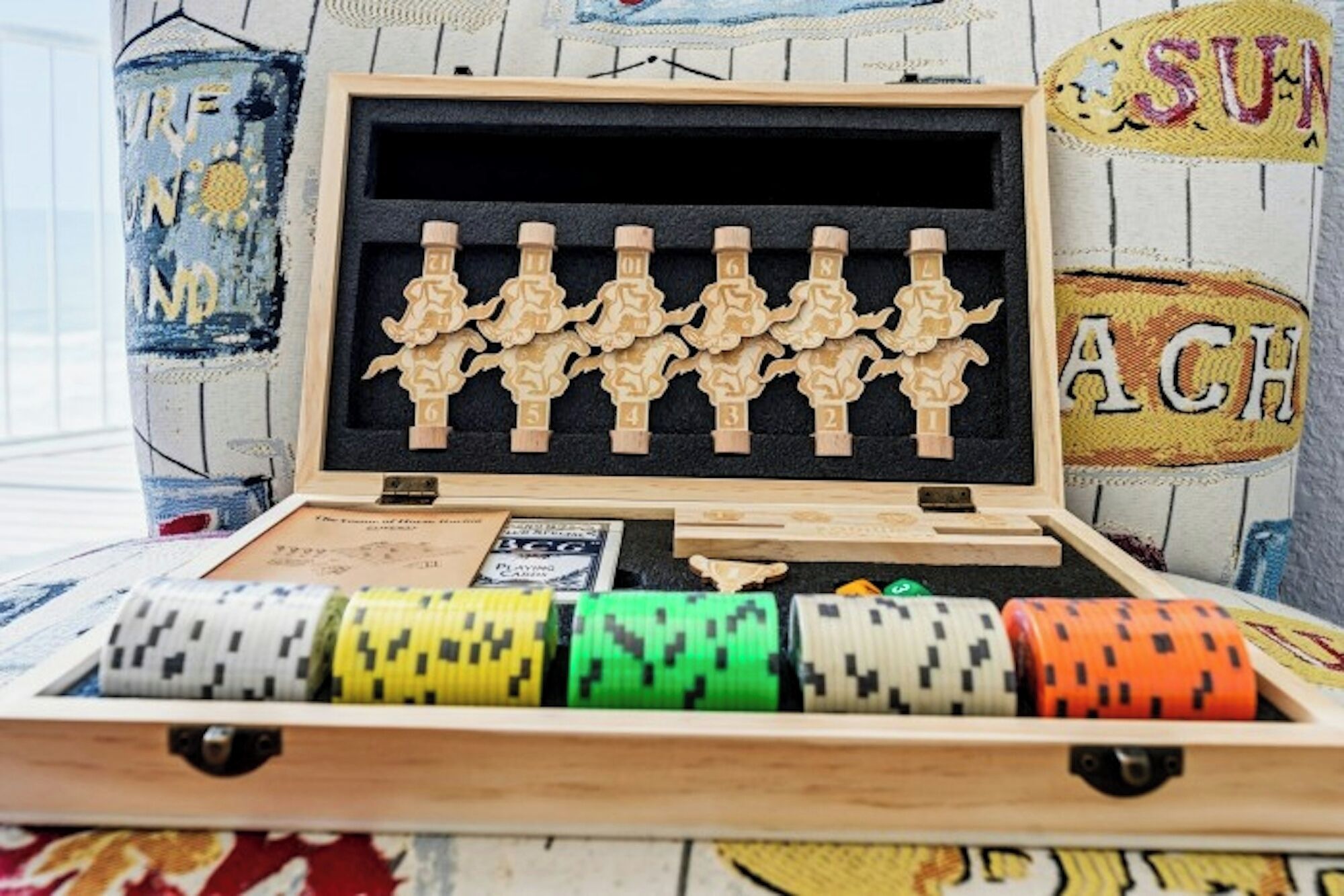 A wooden box with a black interior, containing wooden figurines and poker chips.