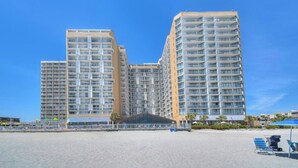 Un hôtel de grande hauteur doté de nombreux balcons, offrant une vue sur la plage et possédant une entrée abritée.