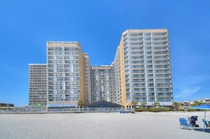 Ein Hochhaus-Hotel mit mehreren Balkonen, Blick auf den Strand und einem überdachten Eingang.