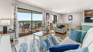 A modern living room with a sofa, coffee table, and a dining area with chairs. - MB Ocean Spa 526-Ocean view, Great Amenities (Myrtle Beach)