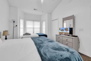 Ein Hotelzimmer mit einem großen Bett, einem Fernseher, einer Kommode und einer Lampe.