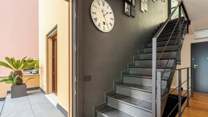 A staircase with a clock, a potted plant, and a door. - Lake Como View 3BR | Regina 35 (Carate Urio)