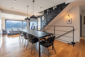 Eine moderne Küche mit einer großen Kochinsel, einer Treppe mit schwarzer Geländer und Blick auf die Berge.
