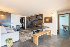 Eine moderne Küche mit dunklen Schränken, einer Holzbänkl und einem Essbereich.