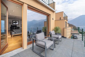 Eine moderne Außenpatio mit Sitzgelegenheit, eine Glastür zu einem Innenwohnraum und Blick auf die Berge.