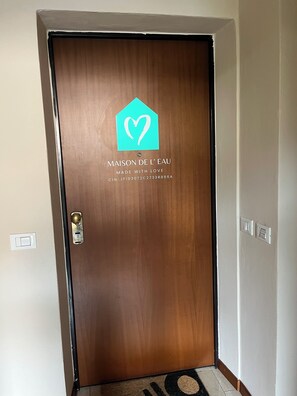 Uma porta de madeira com um logotipo e texto indicando 'MAISON DE L'EAU' e um número de contato.