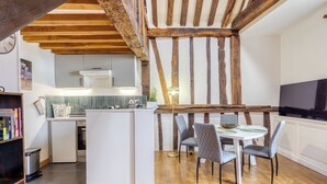 Une cuisine moderne dotée d’un îlot central intégré, de poutres en bois et d’un coin repas avec une table et des chaises.
