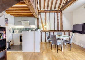 Eine moderne Küche mit integriertem Kochinsel, Holzbalken und einem Essbereich mit Tisch und Stühlen.