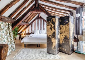 Ein Schlafzimmer mit Holzboden, einem Bett, einer Wand mit Weltkarten und einem Globus.