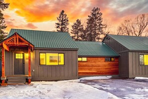 Une cabane avec un toit en métal, des murs en bois et une véranda.
