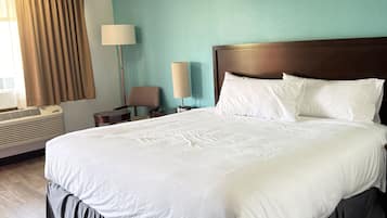 Une chambre d’hôtel avec un grand lit, une table de chevet, une lampe et une fenêtre avec des rideaux.