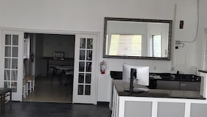 A spacious kitchen with a central island, a dining area with chairs, and a large mirror above the island.