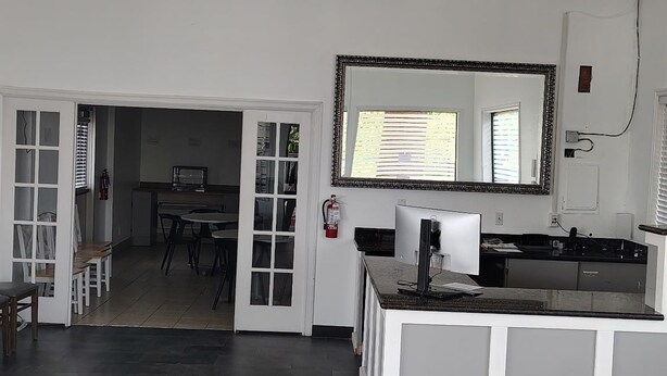 Una cocina amplia con una isla central, una zona de comedor con sillas y un espejo grande sobre la isla.