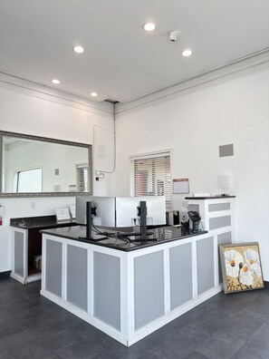 A reception desk with a large mirror, a cash register, and a framed picture on the wall.