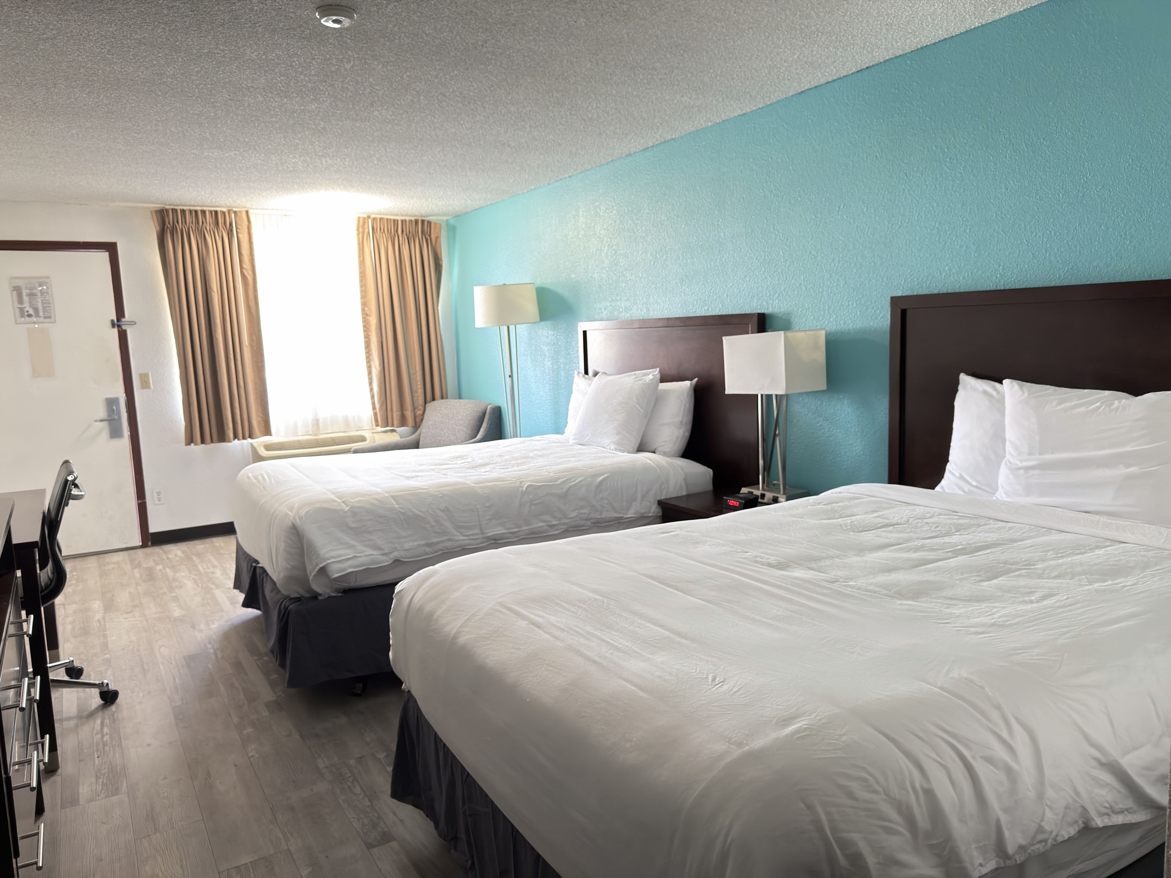 Ein Hotelzimmer mit zwei Betten, einem Schreibtisch und einem Stuhl.