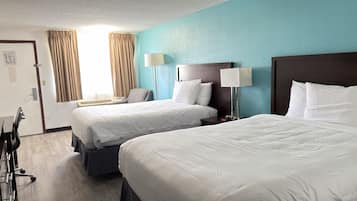 Ein Hotelzimmer mit zwei Betten, einem Schreibtisch und einem Stuhl.