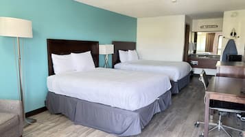 Una habitación de hotel con dos camas, un escritorio, una silla y una lámpara.