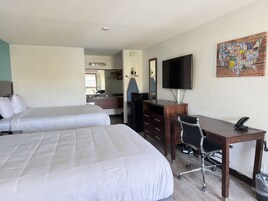 Habitación de hotel con dos camas, un escritorio, una silla, un televisor y una obra de arte colgada en la pared.