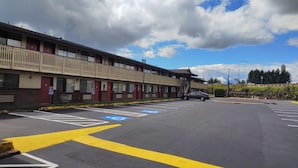 A multi-story parking structure with designated disabled parking spaces, a building with a balcony, and a clear sky.