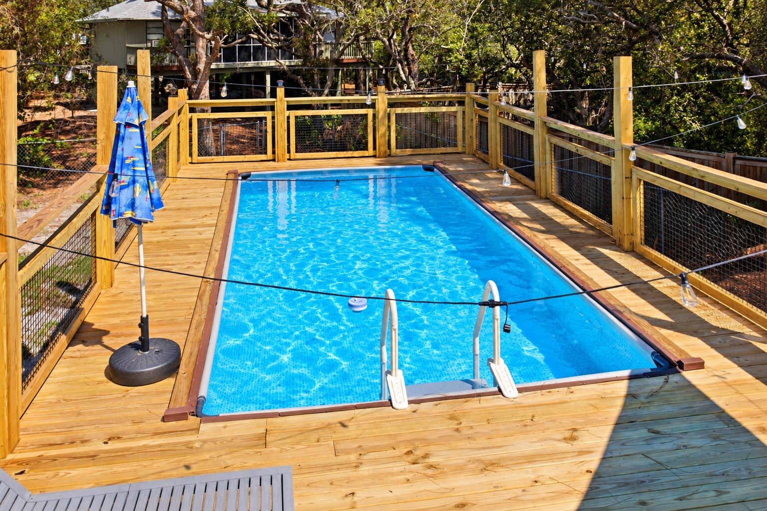 Ein rechteckiger Swimmingpool mit Holzdeck, umgeben von einem Holzzaun und einer Seilsperre.