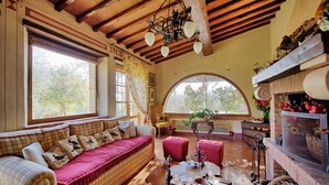 A cozy room with a wooden ceiling, a large window, a fireplace, and a seating area with a sofa and ottoman. - Tuscan oasis overlooking Montepulciano, Villa with pool and exclusive garden (Toscana)