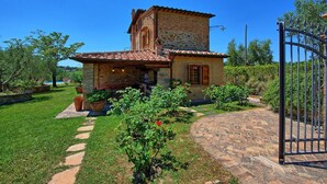 A rustic stone house with a tiled roof, a paved entrance, and a garden with potted plants. - Tuscan oasis overlooking Montepulciano, Villa with pool and exclusive garden (Toscana)