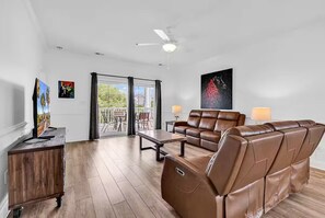 A spacious living room with a brown leather sofa, a wooden coffee table, and a TV on a wooden cabinet. - Magnolia Pointe Suite  Pools Near Beach & Golf (Myrtle Beach)