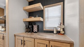 A kitchen with wooden cabinets, a marble countertop, a built-in window with blinds, and various kitchen appliances. - Private Countryside Escape • Deck Views • Near SA (Adkins)