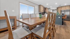 A modern kitchen with wooden cabinets, a dining area with a wooden table and chairs, and a view of the outdoors. - Private Countryside Escape • Deck Views • Near SA (Adkins)