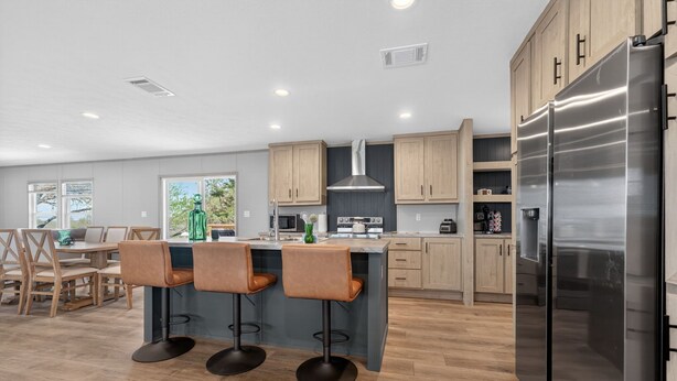 A modern kitchen with wooden cabinets, a stainless steel refrigerator, and a bar area with stools. - Private Countryside Escape • Deck Views • Near SA (Adkins)