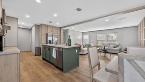 A modern kitchen with a central island, wooden cabinets, and a dining area with a sofa and chairs. - Private Countryside Escape • Deck Views • Near SA (Adkins)