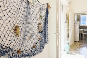 A hallway with a net art installation, a white door, and a view into a kitchen area. - Zaffiro by Casa di Marco (Torre Suda)