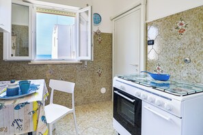 Een koelkast, een oven, een kookplaat, kookgerei, borden en bestek
