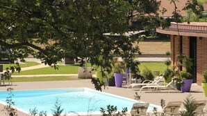 A pool area with lounge chairs and potted plants. - Relais Du Silence Domaine La Charpiniere (Saint-Galmier)