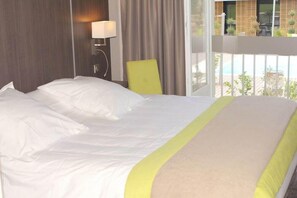 A hotel room with a large bed, a chair, a lamp, and a view of the outdoors. - Relais DU Silence Domaine LA Charpiniere (Saint-Galmier)