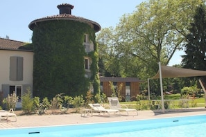 A pool area with lounge chairs, a covered seating area, and a building partially covered with ivy. - Relais Du Silence Domaine La Charpiniere (Saint-Galmier)