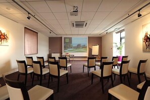 A conference room with a projector screen, a whiteboard, and a table with chairs. - Relais Du Silence Domaine La Charpiniere (Saint-Galmier)